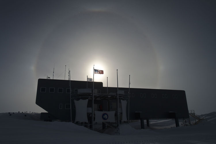 Sundogs behind South Pole station with US flag centered on sun