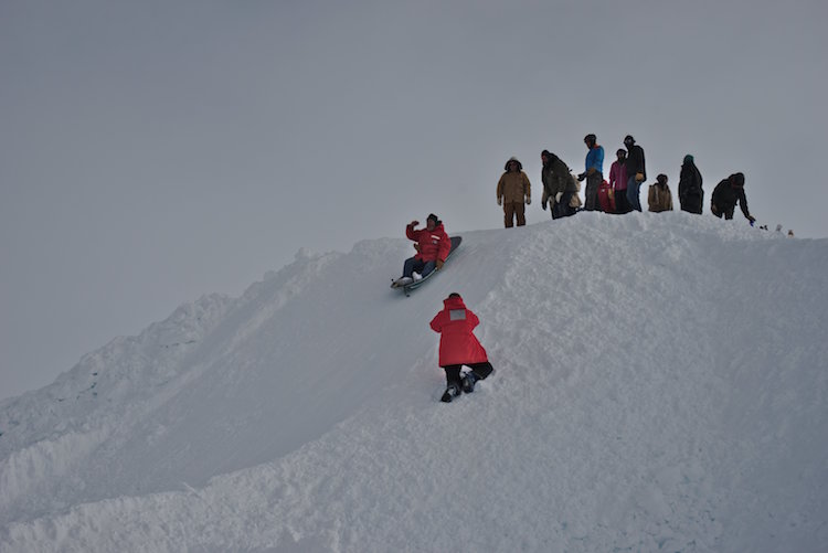Group sledding down small hill at the South Pole.