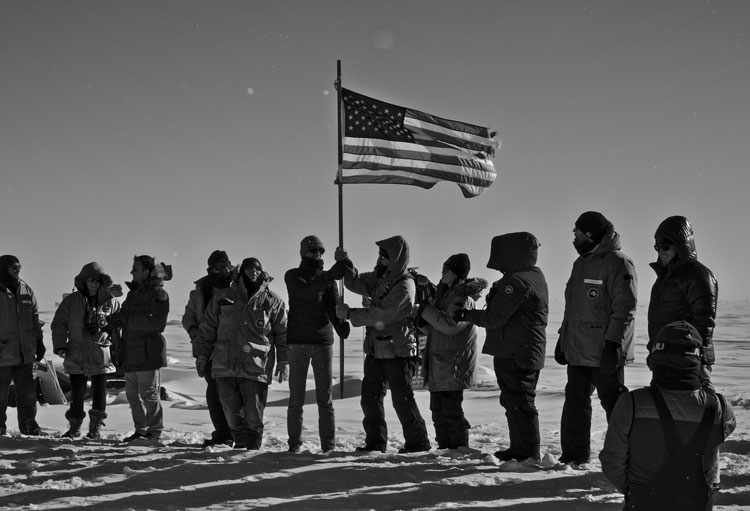 Black and white image of group of people handing around the US flag