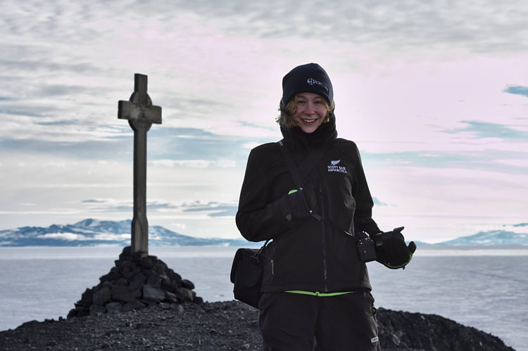 Person smiling for camera, with memorial cross in background
