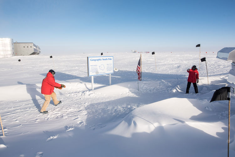 Two people in red parkas playing frisbee outside at South Pole