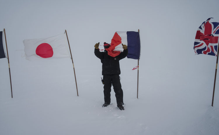 Whiteout conditions with person shown struggling with flapping flags