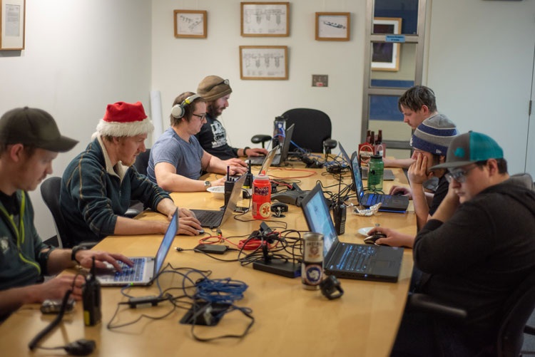 Group of people around a table all looking at their laptops