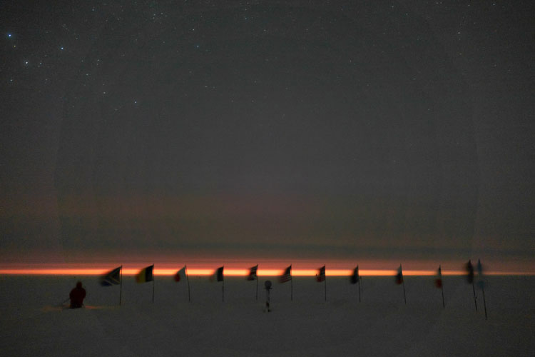 Line of flags in shadow against orange-lit horizon