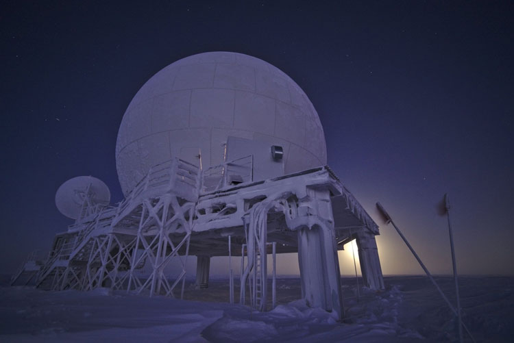 Frosted satellite dome backlit by full moon at South Pole