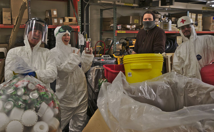 a few people in Tyvek suits, smiling, one holding soda can