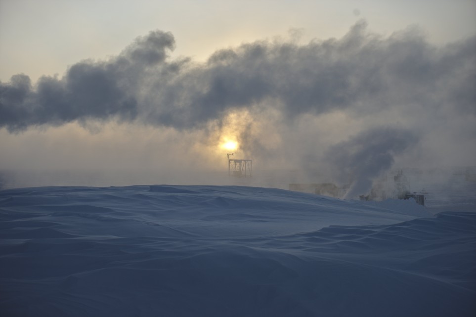 South Pole, with sun low in sky, blocked by wave of exhaust