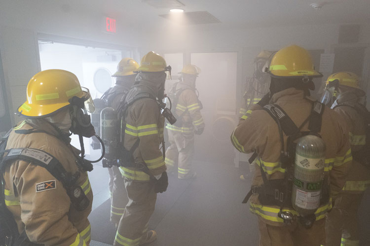 group of firefighters in gear and training for simulated emergency