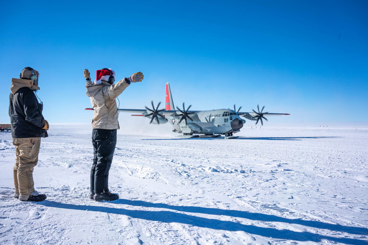 Two people directing a Herc at South Pole under clear skies