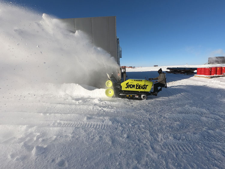 Side view of heavy-duty snow blower blowing snow in front of it