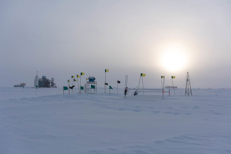 Cluster of flags at South Pole, with sun low in overcast sky