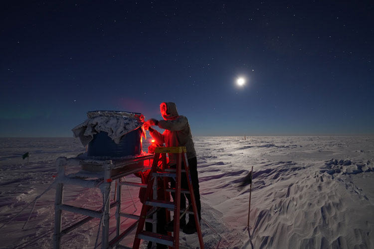 Person working outside at South Pole under bright moon