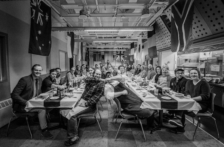 Black and white group shot seated at two long dining tables