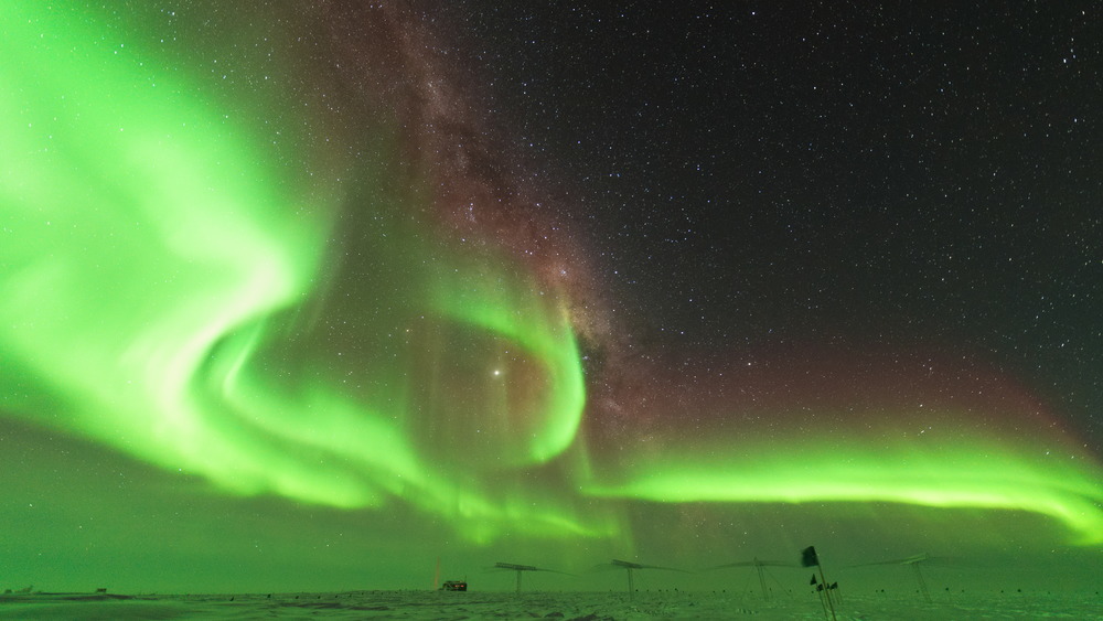 Bright green auroras surrounding Jupiter in South Pole night sky.