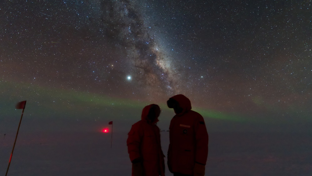 Two people standing outside, auroras and stars in sky