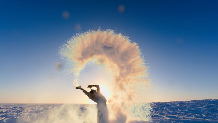 Someone throwing water into an arc of spraying ice crystals