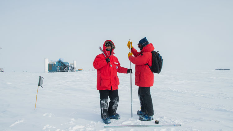 Two people in red parkas out measuring snow depths