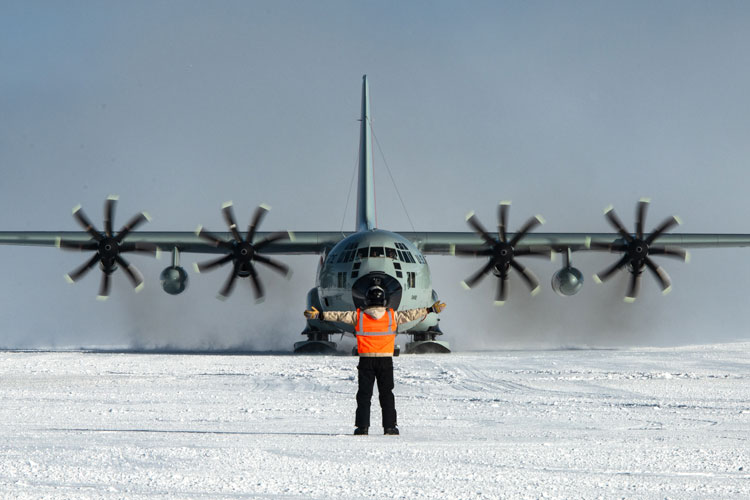 Frontal view of person directing a landed C130 plane