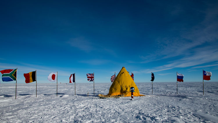 Scott tent flanked by flags on either side at ceremonial South Pole