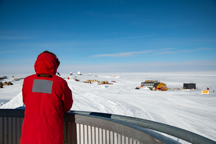 Back of person in red parka looking out on South Pole landscape, waiting
