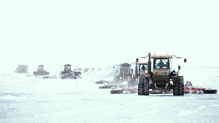 View of convoy of tractors approaching on snow