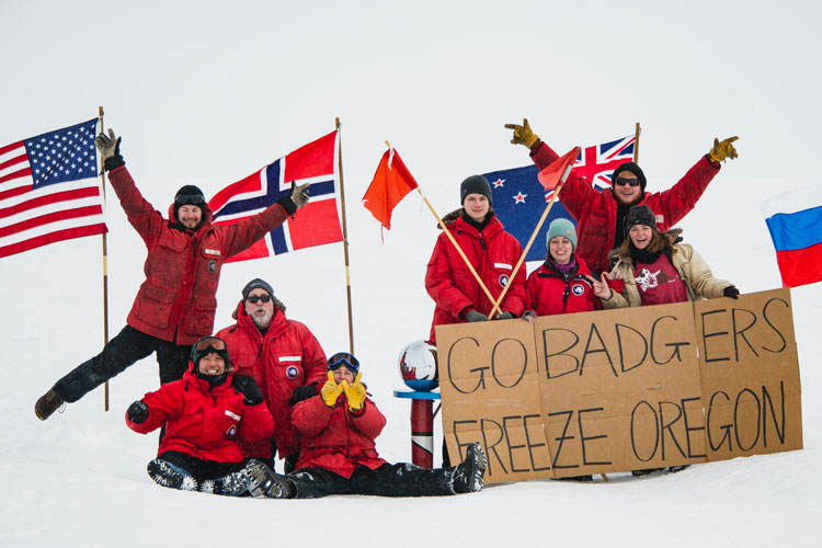 group photo at ceremonial pole holding a "go Badgers" cardboard sign