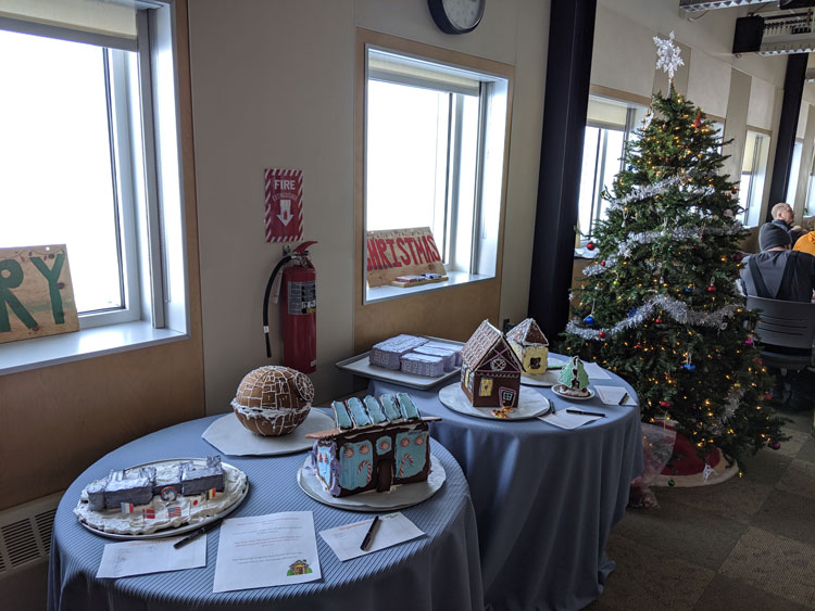 Various gingerbread structures laid out next to decorated Christmas tree
