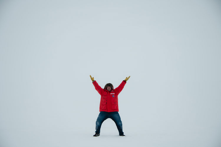 Person outside in red parka with arms up in the air, just white all around due to low visibility
