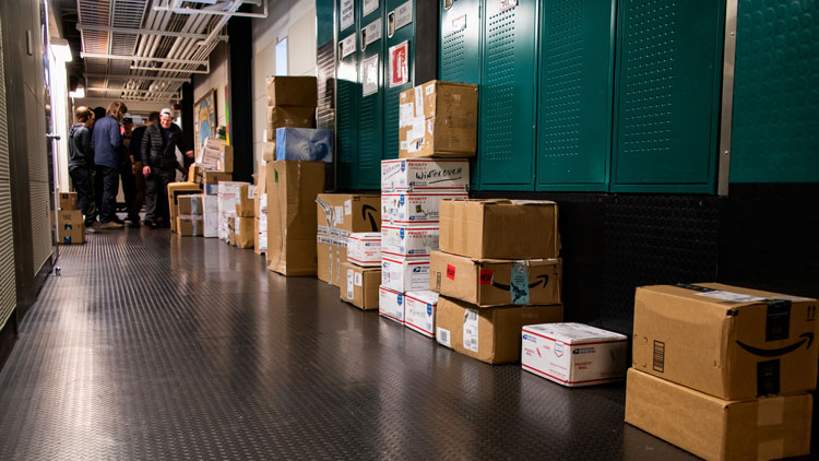 Stacks of boxes on the floor below a row of lockers.