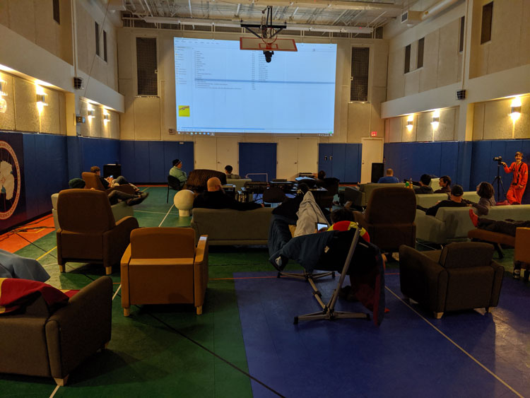 Lounge chairs set up in gym, facing projection screen.