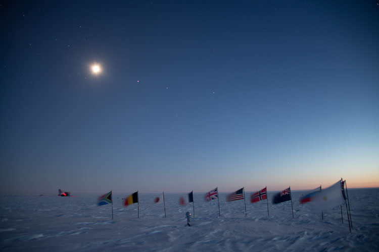 Bright moon with some planets visible over the flags at ceremonial South Pole