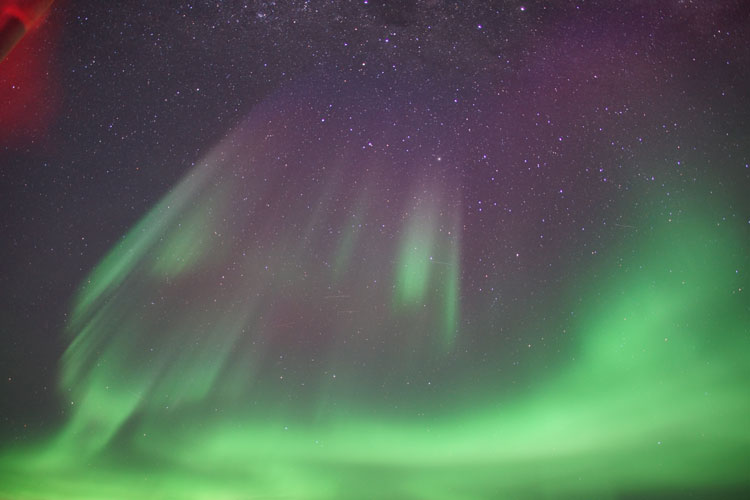 Green auroras that look like suns rays in starry skies