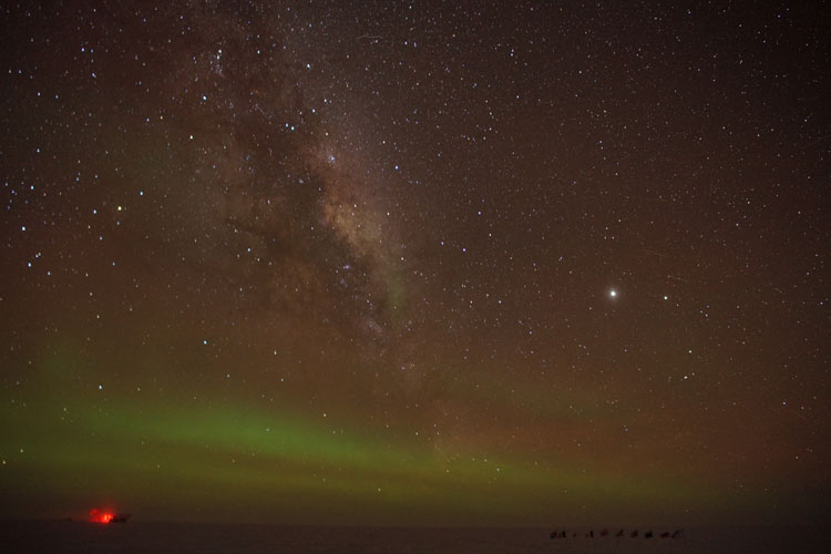 Faint auroras along horizon, starry sky