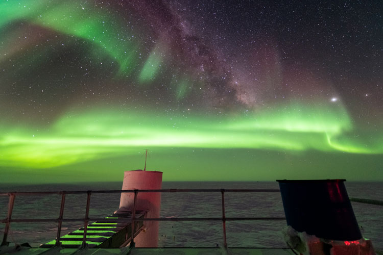 Green auroras in background sky from roof of IceCube Lab