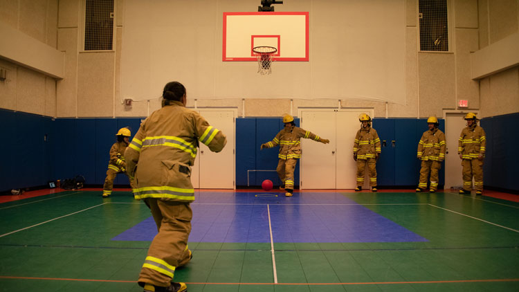 Playing kick ball in gym in firefighting gear