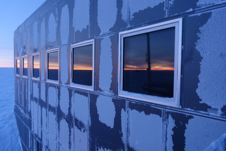 Sunrise on horizon seen as reflection in station windows.