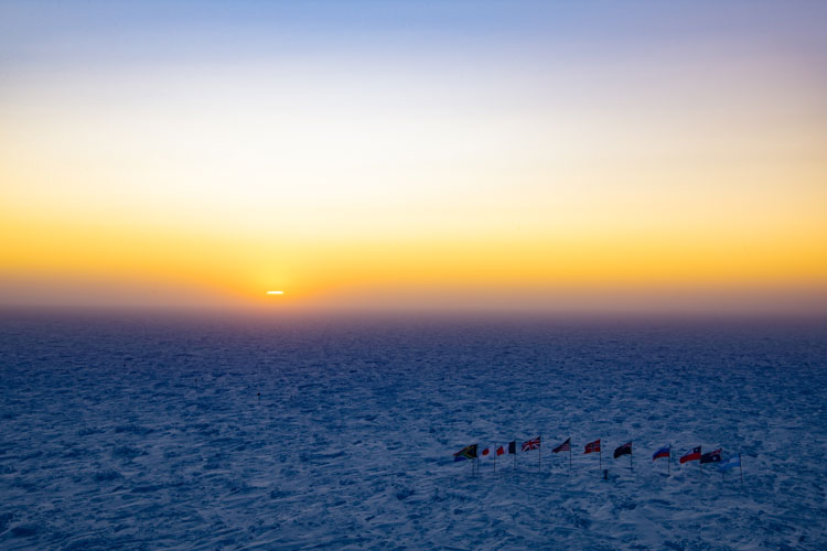 Sunrise on horizon, ceremonial Pole flags closer in foreground