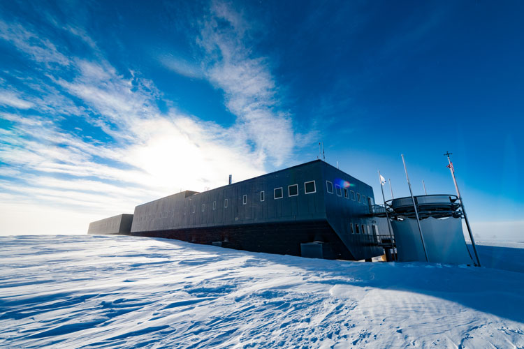 South Pole station under sunny blue sky with some clouds