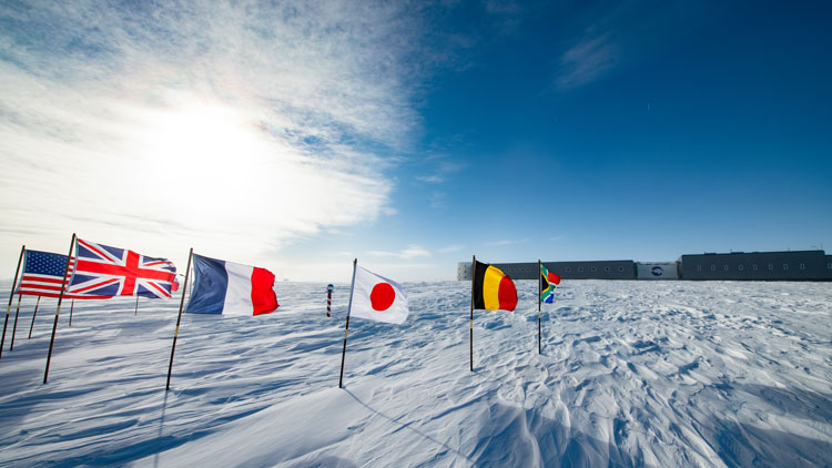 South Pole station in distance, some of the flags at ceremonial pole in foreground