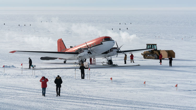 Arriving winter personnel walking away from plane parked on the skiway at South Pole.