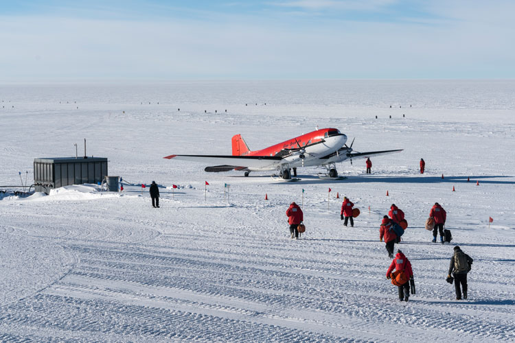 Departing summer personnel walking out to awaiting plane on the skiway at South Pole.