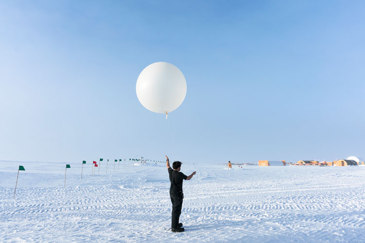Winterover holding onto a weather balloon before launch.