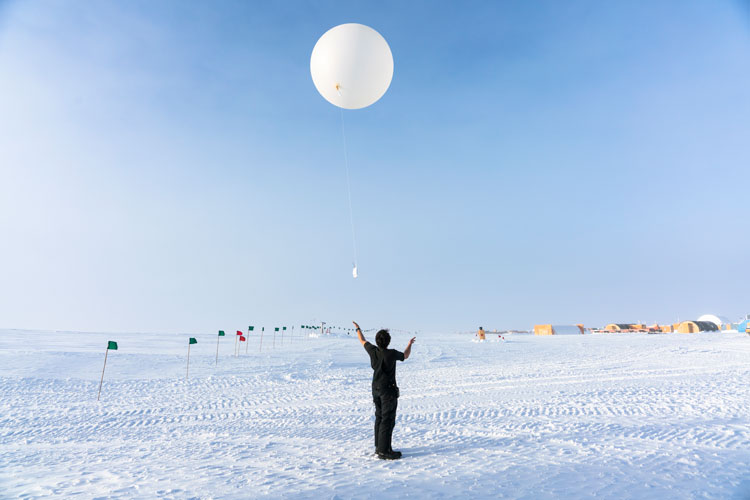 Winterover having just let go to launch a weather balloon.