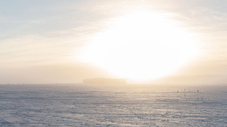 Bright sun low in sky over the South Pole station.