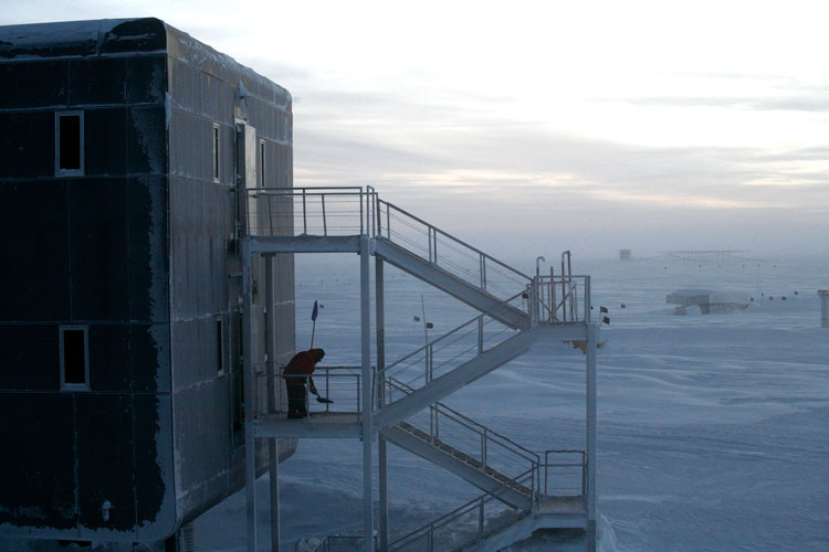 Person shoveling snow away from emergency exits outside the South Pole station.