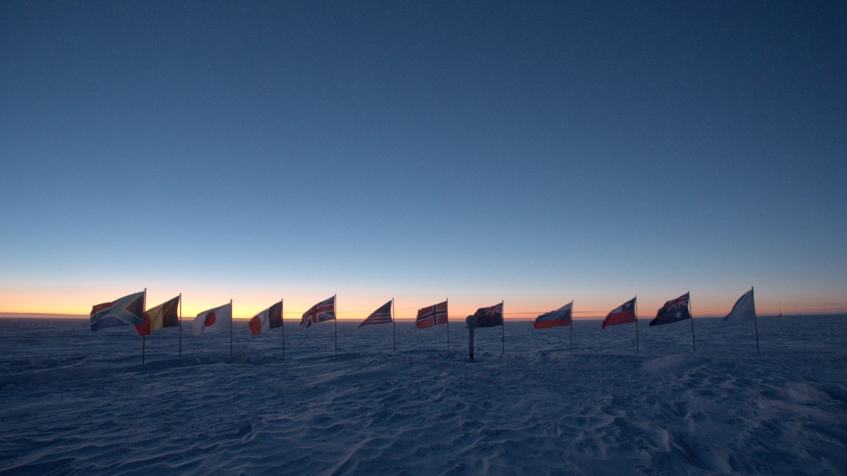  The flags at the ceremonial pole shown in shadow against a colorful horizon.