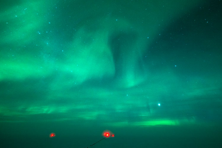 Sky and surface all bathed in green light from auroras.