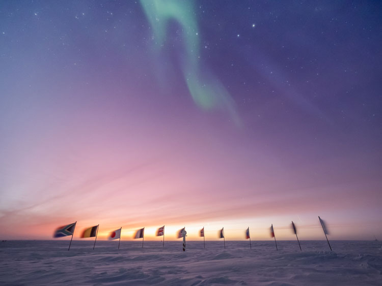 Early sunrise behind the flags at the ceremonial South Pole.
