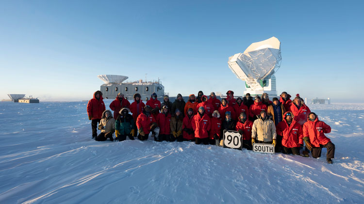 South Pole station winterovers posing as a group behind the South Pole Telescope.