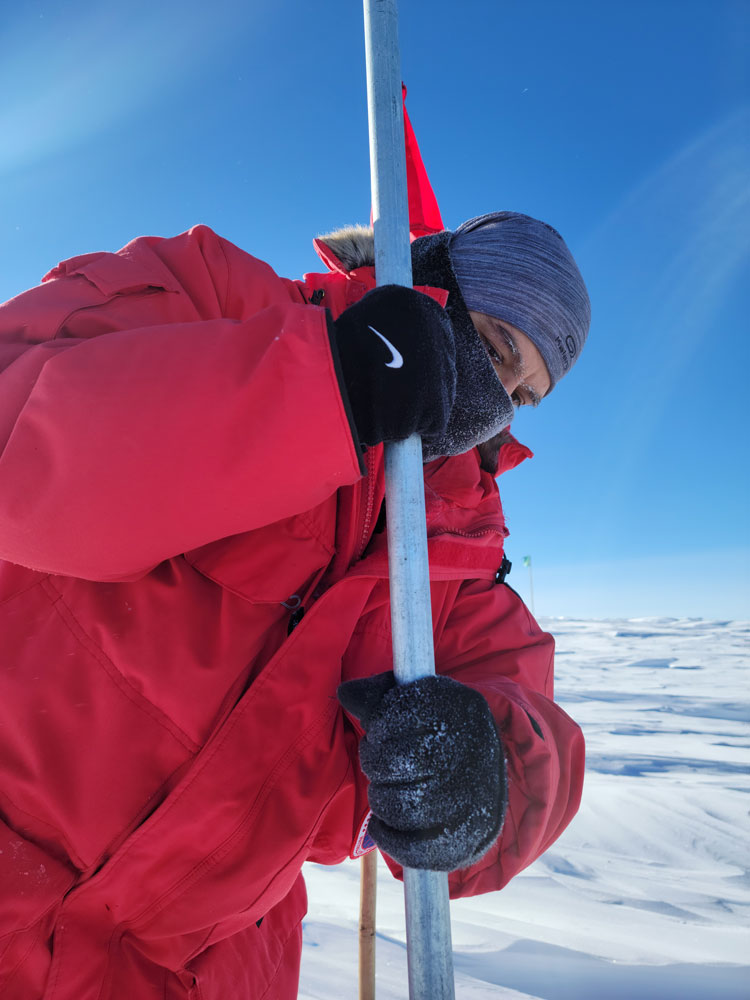 Close-up of person in red parka with long measuring stick.